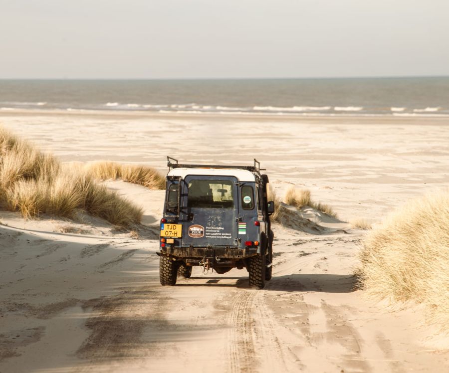 Een landrover van Puur Terschelling rijdt het Noordzee strand op voor een avontuurlijke tocht
