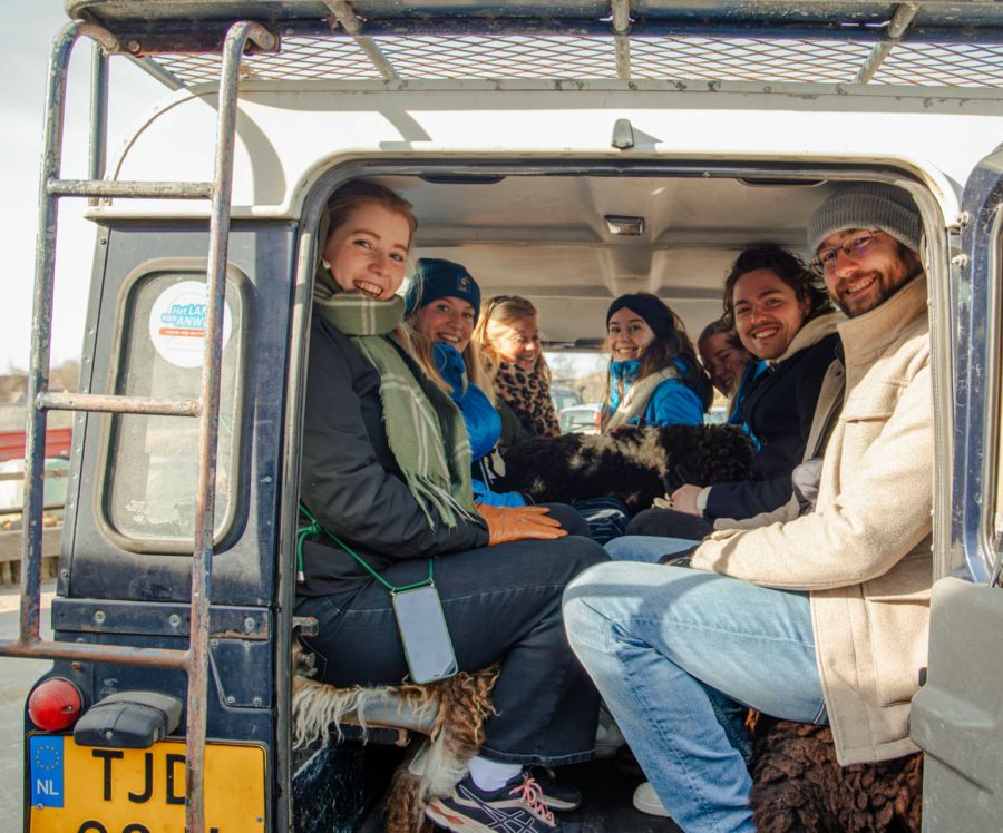 Een groep mensen zit achterin een Landrover tijdens een tocht over het strand op Terschelling
