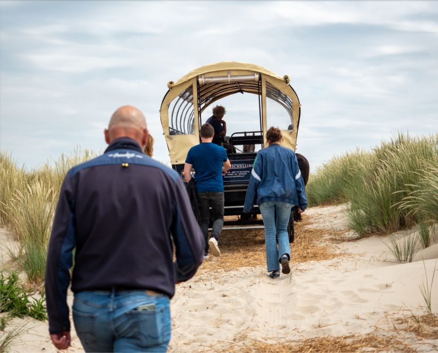 Gasten lopen naar een huifkar van Puur Terschelling in de duinen bij het Noordzee strand